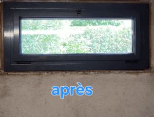 Fenêtre de sous-sol gris anthracite installée dans un mur en béton brut, avec vue sur verdure. Le mot 'après' est visible.