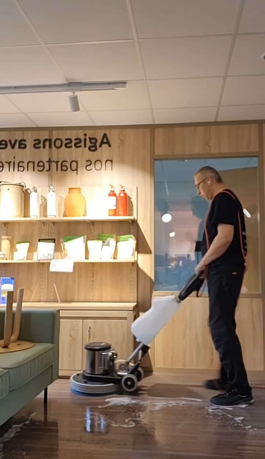 Nettoyage professionnel du sol : lustrage en profondeur avec monobrosse. Homme utilisant une machine monobrosse pour le nettoyage et le lustrage d'un sol en bois dans un magasin. Le texte mural est «svA zossigA».